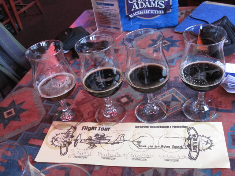 A tasting flight of craft beers in small glasses lined up on a bar