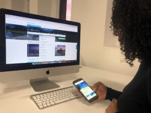 A person comparing travel booking websites on a desktop computer and smartphone